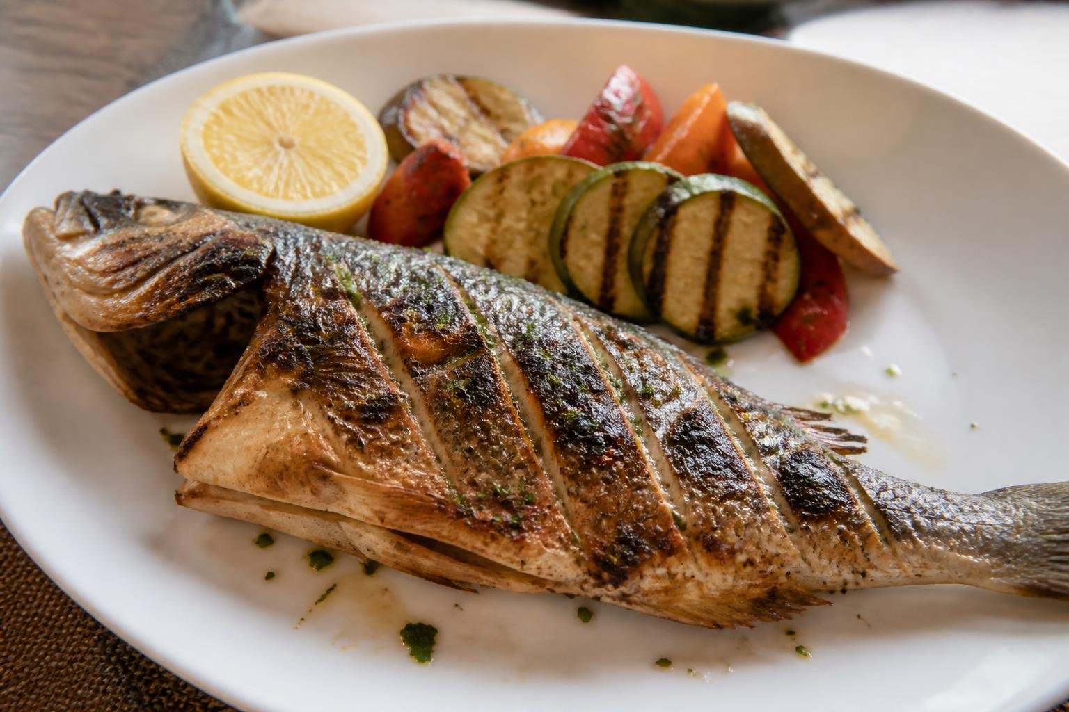 Poisson grillé accompagné de légumes, présenté en assiette de restaurant