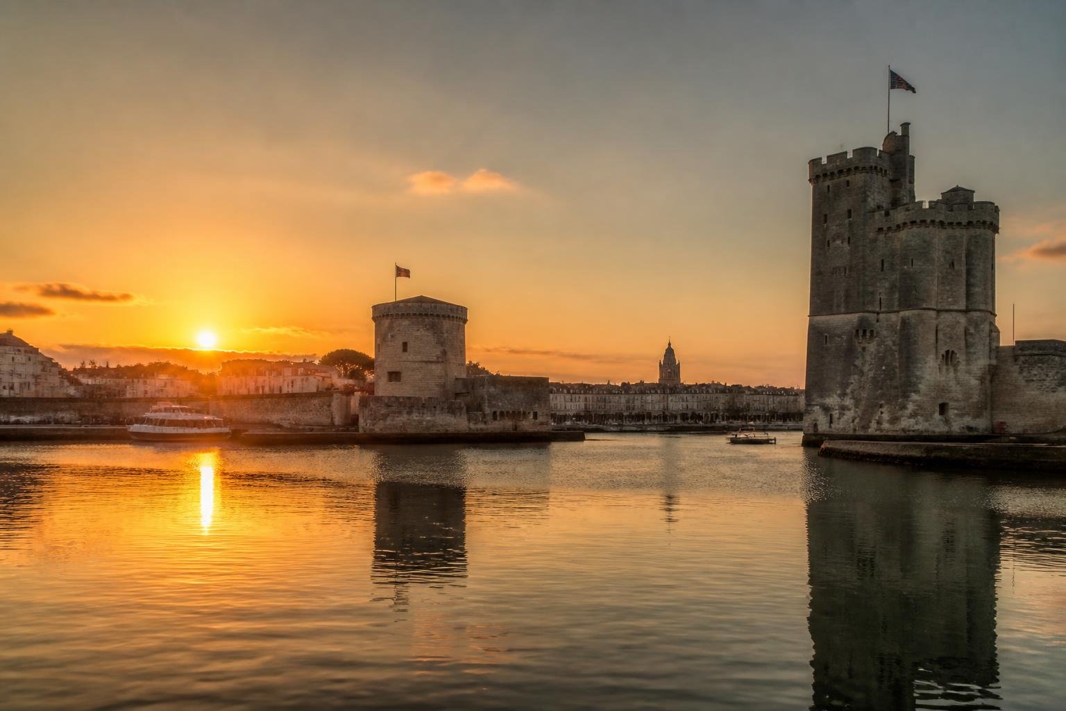 Vue sur le vieux port de La Rochelle avec ses trois tours emblématiques au coucher de soleil